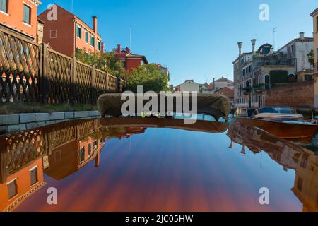 Elegante motoscafo in legno viaggia sul canale d'acqua con Casa in un giorno di sole a Venezia, Veneto in Italia. Foto Stock