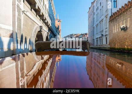 Elegante motoscafo in legno viaggia sul canale d'acqua con Casa in un giorno di sole a Venezia, Veneto in Italia. Foto Stock