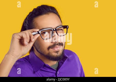 Curioso giovane uomo indiano in occhiali guarda la macchina fotografica con sospetto volto espressione Foto Stock