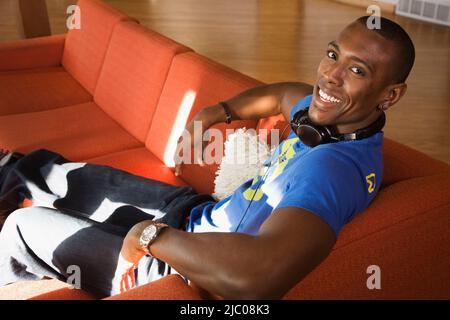 Giovane uomo che indossa le cuffie intorno al suo collo Foto Stock
