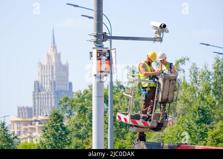 Mosca. Russia. Giugno 9, 2022. Gli ingegneri su una gru a torre riparano una telecamera TVCC su un palo in città. Messa a fuoco selettiva. Foto Stock