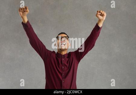 L'uomo afroamericano clench pugno in piedi con le mani alzate in su celebrare la vittoria Foto Stock