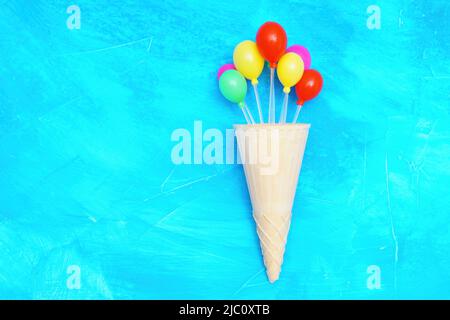 Gruppo di palloncini colorati in plastica in un cono di waffle che imita il gelato. Vivido concetto di festa. Foto Stock