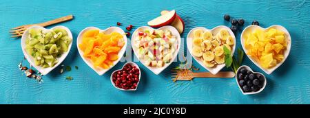 Piatti di frutta a forma di cuore su sfondo blu o ciano Foto Stock