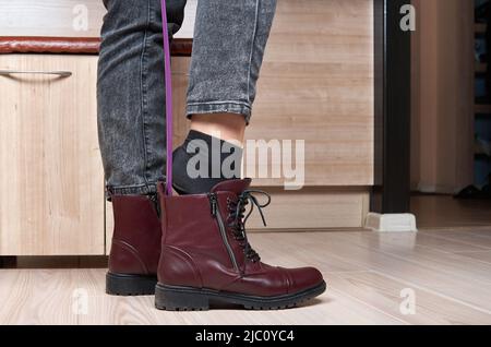 Donna che indossa scarpe rosse con calzascarpe. Foto Stock