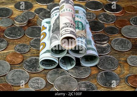 Banconote in dollari americani arrotolate in tubo e monete statunitensi. Cassa e risparmio di attività finanziarie e di finanziamenti per la casa durante la crisi economica. Primo piano. Foto Stock