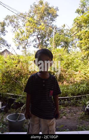 foto a luce bassa di un ragazzo che gioca di fronte alla casa Foto Stock