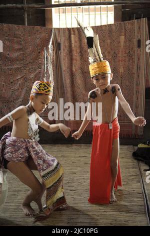 Bambini in abbigliamento tradizionale che eseguono una danza tradizionale durante un evento di ecoturismo alla solitudine della tradizionale comunità IBAN di Dayak a Sungai Utik, Batu Lintang, Embaloh Hulu, Kapuas Hulu, West Kalimantan, Indonesia. Foto Stock