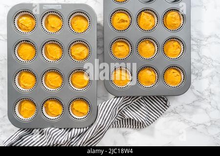 Disposizione piatta. Impasto per cupcake con spezie di zucca in una padella con rivestimenti. Foto Stock