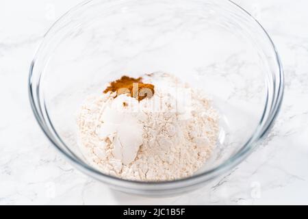 Mescolare gli ingredienti secchi in un recipiente grande in vetro per cuocere morbidi biscotti alla noce di uvetta con farinata d'avena. Foto Stock