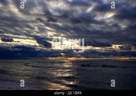 Il mare e i raggi del sole fanno il loro senso attraverso le nuvole. Tramonto sul Mar Baltico Foto Stock