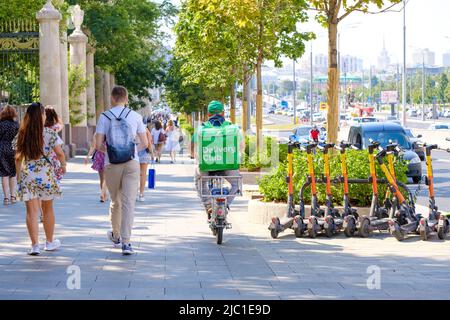 Mosca. Russia. Giugno 9, 2022. Il corriere del club di consegna corre una bicicletta sul marciapiede in una giornata estiva soleggiata. Un corriere con una grande scatola termale verde consegna il cibo su una bicicletta a Mosca. Foto Stock