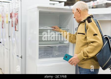 senor uomo pensionato acquistare frigorifero in showroom di elettrodomestici negozio Foto Stock