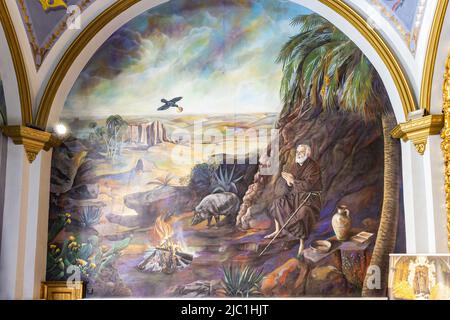 Trigueros, Huelva, Spagna - 17 aprile 2022: Affresco di San Antonio Abad (Sant'Antonio Abate) in preghiera, santo di Trigueros, dipinto nel muro Foto Stock