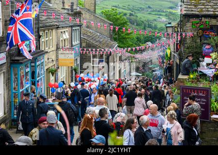 Il fine settimana di Haworth 1940 (affollata strada panoramica Main Street decorata in rosso bianco blu Union Jacks, popolare giorno-out di famiglia) - West Yorkshire, Inghilterra Regno Unito. Foto Stock