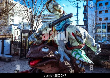 Scultura di rane combattendo vicino all'ingresso di Nawate dori nel centro giapponese Foto Stock