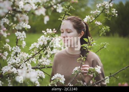 Romantico giovane donna nel giardino di primavera tra Apple Blossom. Foto Stock