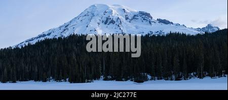 La cima innevata del Monte Rainier sopra un ghiaccio sul Lago di Reflection nel Parco Nazionale del Monte Rainier. Foto Stock