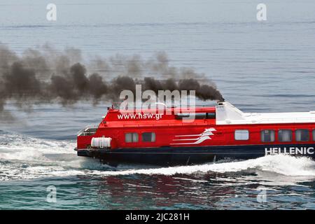 AEGINA, Grecia, - maggio 2022: Primo piano del ripostino di un traghetto veloce con aliscafo che accelera con fumo nero spesso che esce dai suoi imbuti. Foto Stock