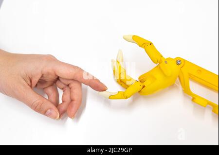 Mano della donna e protesi di plastica per un bambino su sfondo bianco. Foto Stock