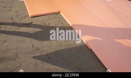 La lastra di polistirene polyplex è posata su sabbia bagnata come isolante per la fondazione di una piscina all'aperto. Foto Stock