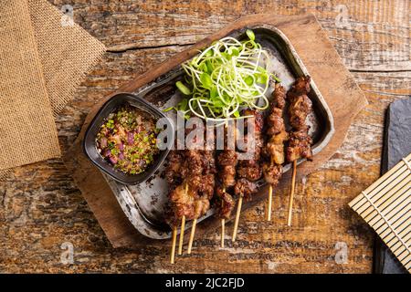 Grigliate in sirloin sulla padella calda decorata con germogli di girasole. Cibo thailandese, vista dall'alto, giorno del cibo mondiale Foto Stock