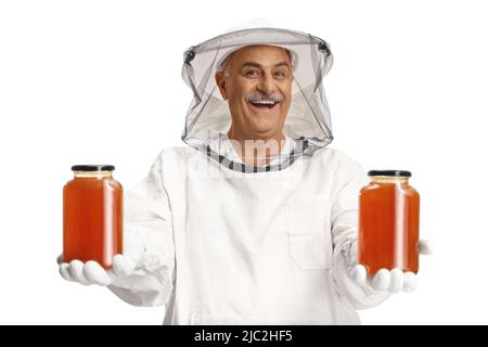 Apicoltore in uniforme che tiene giare di miele e sorridente isolato su sfondo bianco Foto Stock