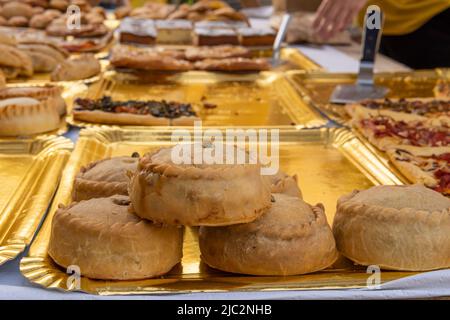 Primo piano di dolci fatti con pasta di lardo, farciti di carne, piselli e sobrasada, chiamati panades. Gastronomia tipica dell'isola di Maiorca, Spagna Foto Stock