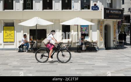 Ixelles, capitale di Bruxelles Regione - Belgio - 06 22 2020 - giovane donna attraente in bicicletta passando una panetteria locale Foto Stock