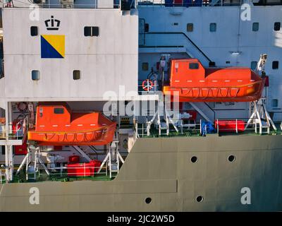 Due barche di salvataggio marine arancioni, ad alta visibilità, pronte per il lancio, sospese tra le navette bianche di lancio su una nave di supporto del Mare del Nord nel porto di Aberdeen. Foto Stock