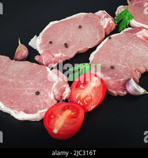 Varietà di bistecche di carne di manzo cruda con ingredienti per cucinare su sfondo scuro Foto Stock
