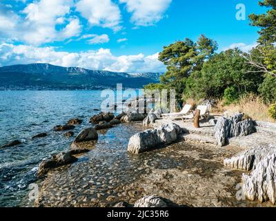 Spiaggia di Kupalište bene con sedie a sdraio presso la costa rocciosa del Parco della Foresta di Marjan nella città di Spalato, Croazia Foto Stock