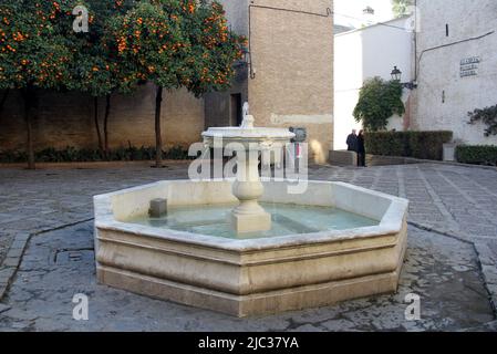 Scena di strada in una piccola piazza con fontana d'acqua vecchia, Plaza de la Alianza, al di fuori delle mura dell'Alcazar, Siviglia, Spagna Foto Stock