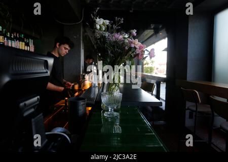 Un giovane lavora al bar in una bella giornata estiva di sole a Kiev nel 2022. La città ha appena iniziato a recuperare da molto turbolento inverno e primavera Foto Stock