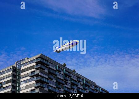 Zeppelin con la pubblicità stampa BUON ANNO vola in cielo blu passando una gru edificio a Colonia. Renania settentrionale-Vestfalia, Germania, 22.5.22 Foto Stock