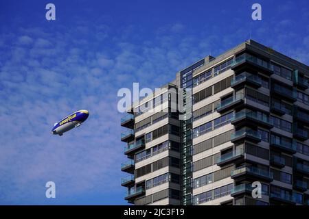 Zeppelin con la pubblicità stampa BUON ANNO vola in cielo blu passando una gru edificio a Colonia. Renania settentrionale-Vestfalia, Germania, 22.5.22 Foto Stock