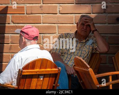 Medellin, Antioquia, Colombia - Febbraio 19 2022: Un uomo dai capelli grigi tiene la fronte con la mano su un patio che guarda infastidito e stanco contro un Re Foto Stock