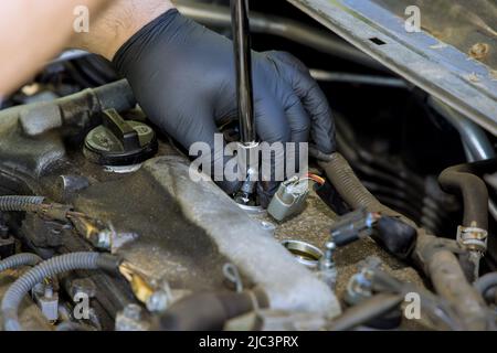 Il meccanico automatico effettua le riparazioni in servizio di garage con svita vecchie candele auto sono sostituite Foto Stock