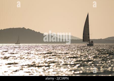 Barche a vela in mare al tramonto Foto Stock