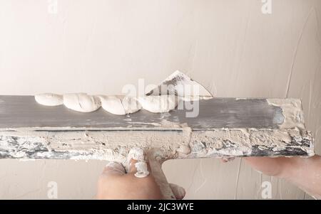 Costruisci intonacature con spatola e levigare la parete con intonaco. Foto Stock