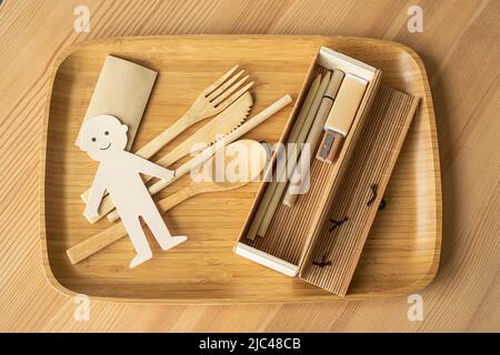 Foto di eco concetto di produzione senza rifiuti, uomo gioioso taglio carta con stoviglie in legno, matita e strumenti di scrittura. Non inquinante Foto Stock