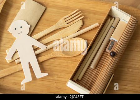 Foto di eco concetto di produzione senza rifiuti, uomo gioioso taglio carta con stoviglie in legno, matita e strumenti di scrittura. Non inquinante Foto Stock