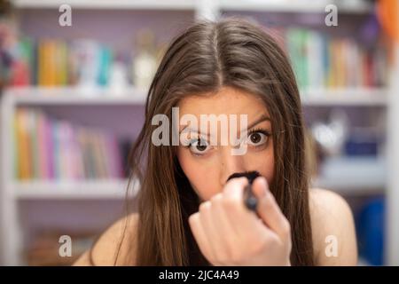 Una ragazza adolescente le polverizza il naso mentre lei dipinge il suo trucco. Vista ravvicinata. Foto Stock