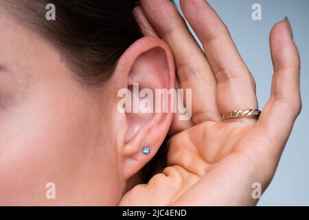 Primo piano di Una donna che cerca di ascoltare con la mano sull'orecchio Foto Stock