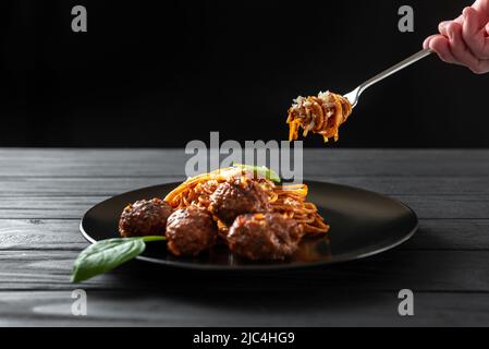 Forchetta con pasta tradizionale italiana con palle di carne e salsa di pomodoro. Pasta cotta secondo una ricetta italiana classica con salsa di pomodoro rosso e. Foto Stock