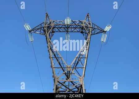 Poli elettrici e linee ad alta tensione su sfondo cielo blu. Foto Stock