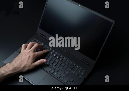 Tastiera per computer portatile con mani utente o giocatore su sfondo nero elegante. Tecnologia, business, concetto internet. Foto di alta qualità Foto Stock
