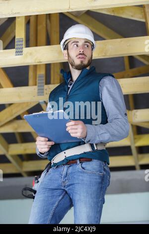 Builder maschio sul tetto di una cornice di legno house Foto Stock