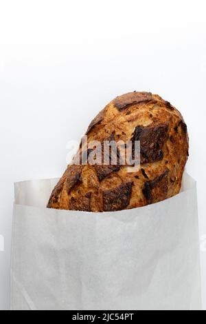 pane tradizionale fatto in casa appena sfornato in sacchetto di carta isolato su sfondo bianco, vista dall'alto, pagnotta intera di pane rustico di cereali biologici con cipolle Foto Stock