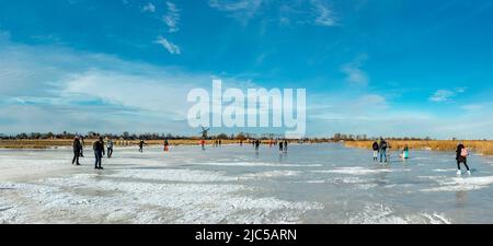 Scrating su un canale congelato vicino ad un mulino a vento locale Caption *** Paesi Bassi,mulino a vento, acqua, inverno, neve, ghiaccio, Persone, Scrateri, ,Westzaan, Noord- Foto Stock